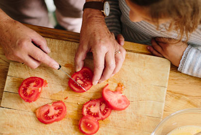 Mom cutting tomatoes for meal in kitchen