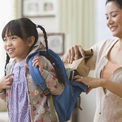 Mom packing child's backpack with food